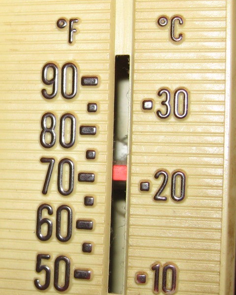 Close-up of a wall thermostat dial set near 70 degrees Fahrenheit