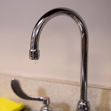 Kitchen faucet with a drop of water hanging from the spout