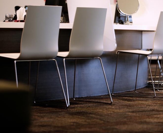 A row of white salon chairs pulled up to a styling counter with a round mirror