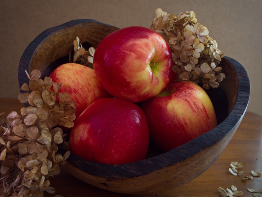 Red and yellow apples piled in a wooden bowl