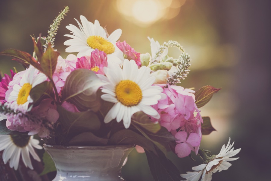 White daisies and pink hydrangea spilling from a grey stoneware pot