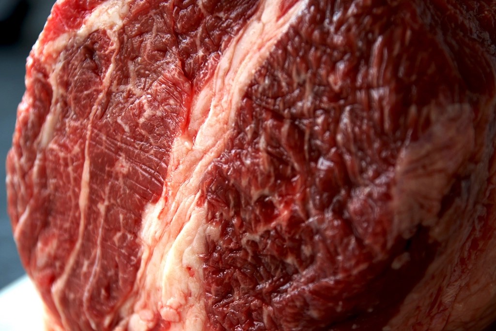 Close view of a raw ribeye with fine white marbling running through deep red muscle