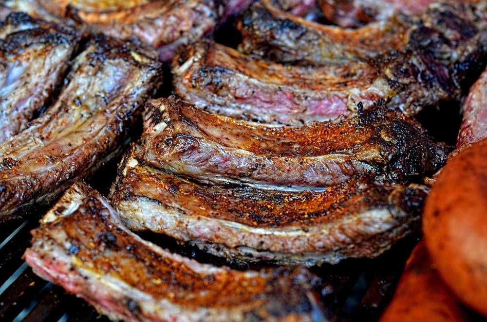 Close view of smoked pork ribs with dark peppery bark and a pink edge