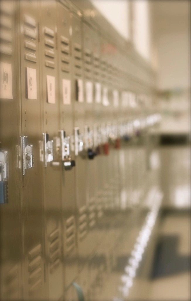 A row of grey metal lockers running down an empty school hallway